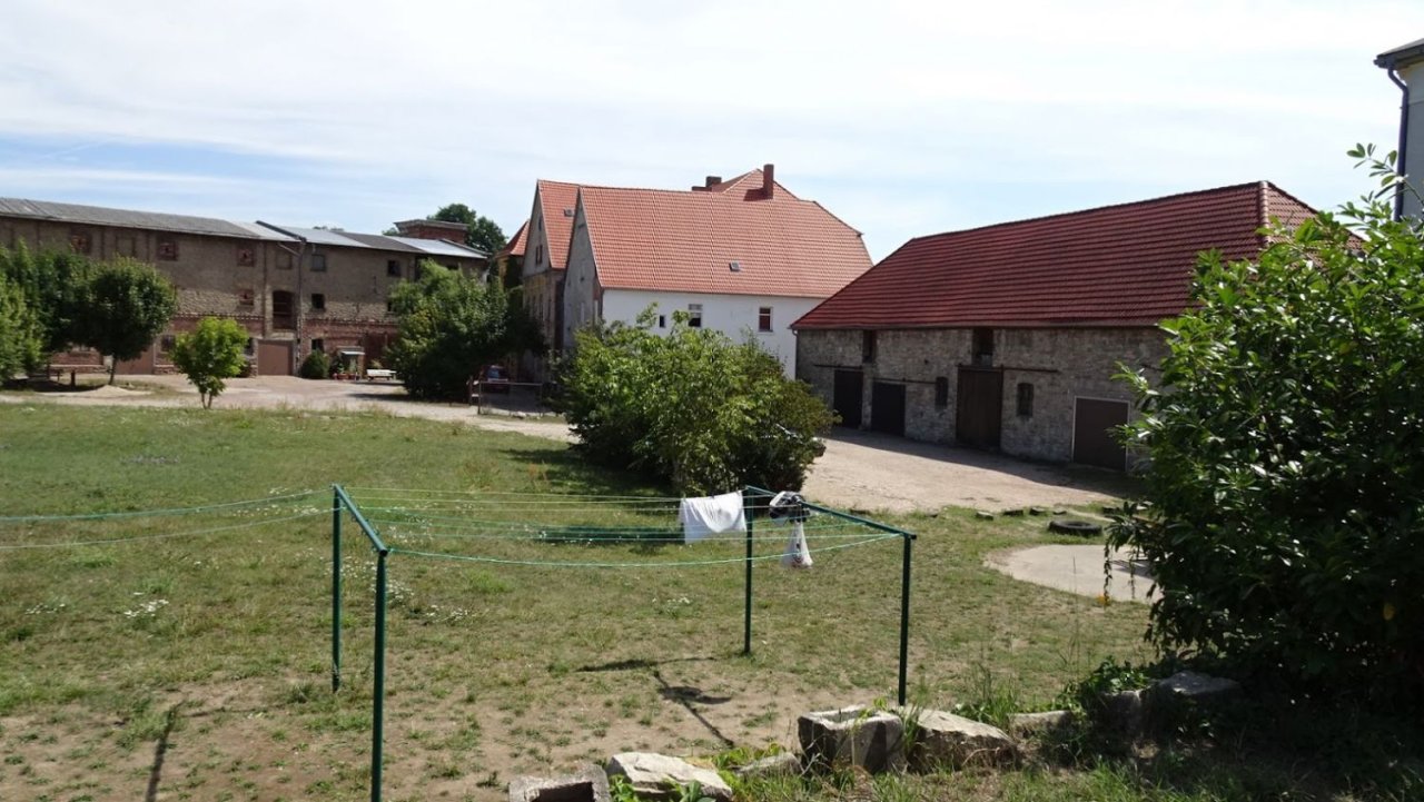 Hoffläche mit Scheunen u. Gutshaus im Hintergrund